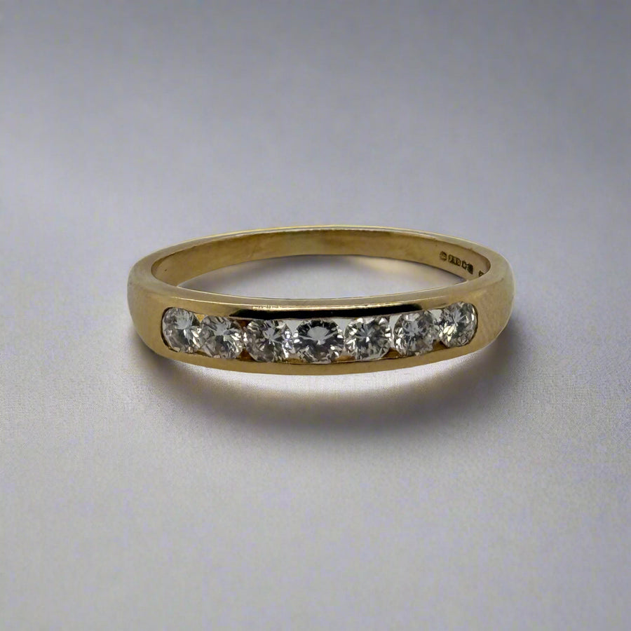 Gold ring with embedded diamonds on a light gray background