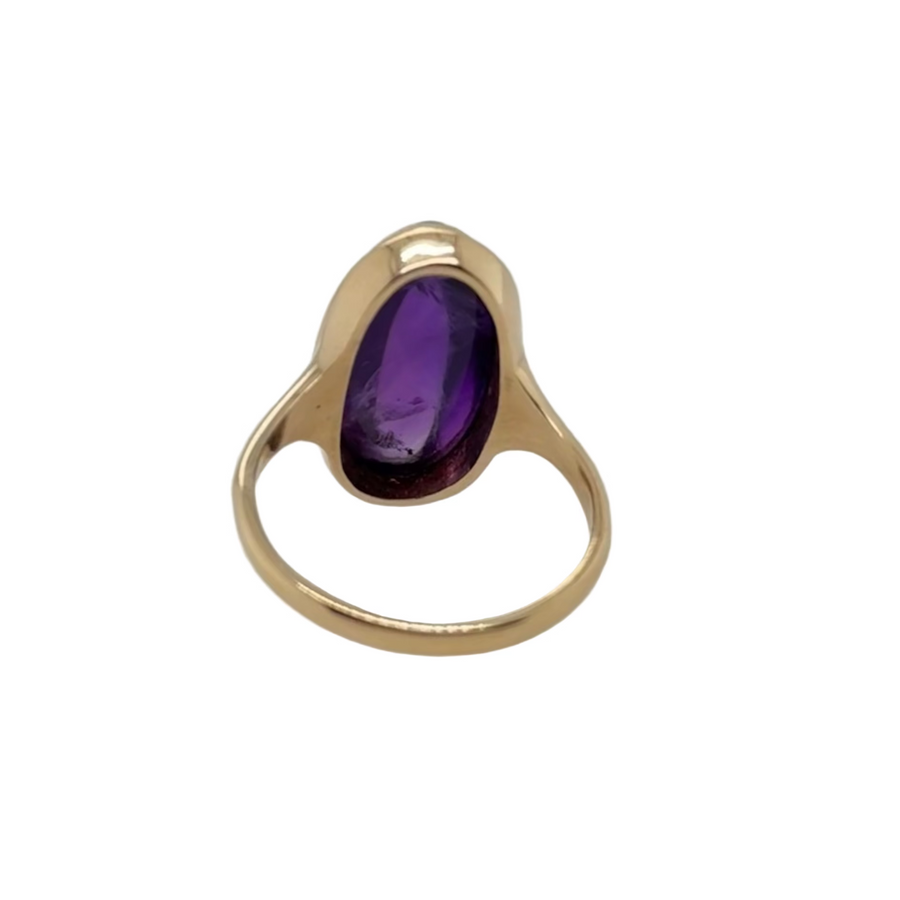 Gold ring with a purple gemstone on a light gray background
