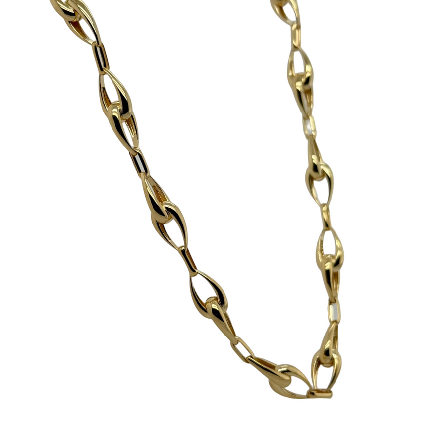 Gold chain necklace on a white stand with a gray background
