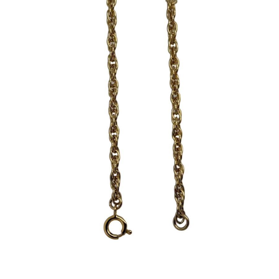 Gold chain necklace on a white stand with a gray background